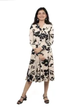 Woman wearing a beige and black floral midi dress, front view, standing and smiling