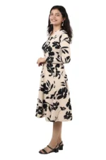 Woman in a beige and black floral midi dress, angled side view, smiling