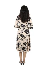 Woman showing the back view of a beige and black floral midi dress, long sleeves