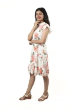 Woman in a white floral ruffle dress, side view, hand on chin, smiling