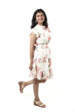 Woman in a white floral ruffle dress, side view, playful pose with one leg up