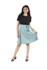 Woman wearing a black top and light blue skirt, front view, playful pose