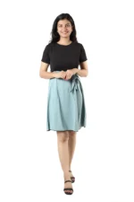 Woman in a black top and light blue skirt, front view, hands folded and smiling