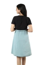Woman showing the back view of a black top and light blue skirt, hands on waist
