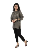 Woman in a grey embroidered kurti with black pants, side view, smiling