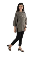 Woman in a grey embroidered kurti with black pants, angled side view, smiling