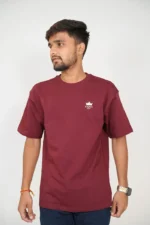 Man standing front-facing wearing maroon t-shirt and black jeans.