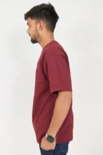 Side view of a man wearing maroon t-shirt and dark blue jeans.