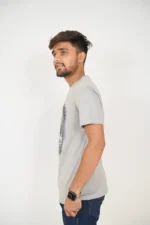 Man posing from left side wearing grey t-shirt and jeans