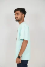 Man in mint blue casual t-shirt and denim jeans posed left side