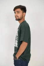 Man standing in left profile wearing dark green short sleeve t-shirt