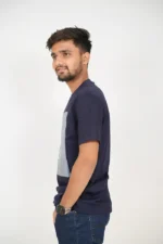 Man wearing plain navy blue t-shirt standing in left profile