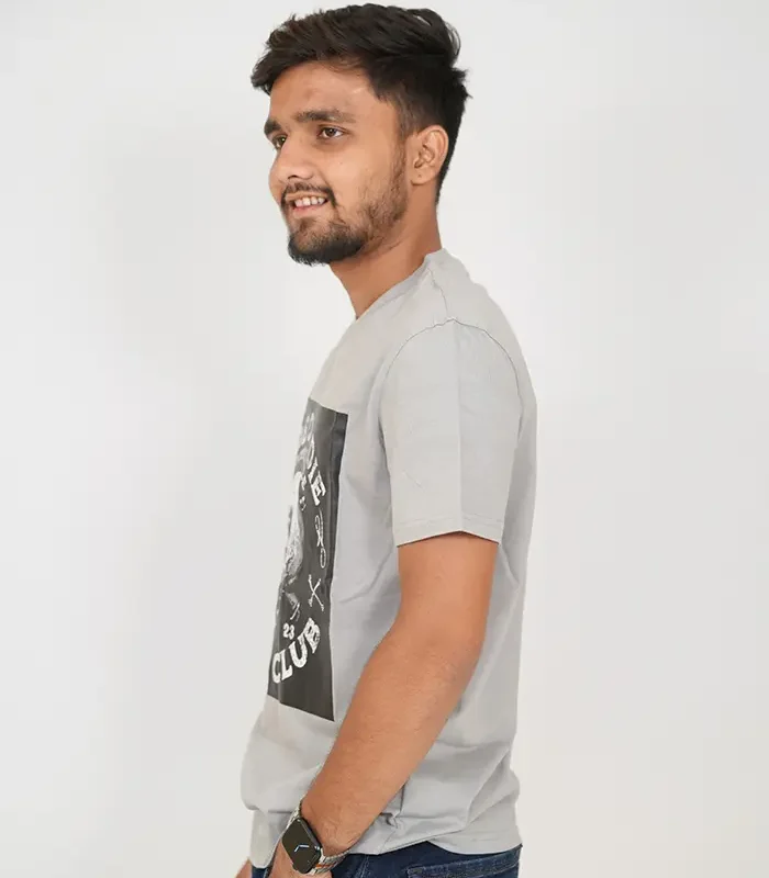 Man in light grey t-shirt and dark jeans posing from left side