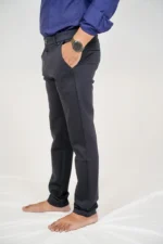 Man wearing black formal trousers and blue shirt, left side view, hand in pocket