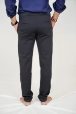 Man in black formal trousers and blue shirt, back view, hands in pockets